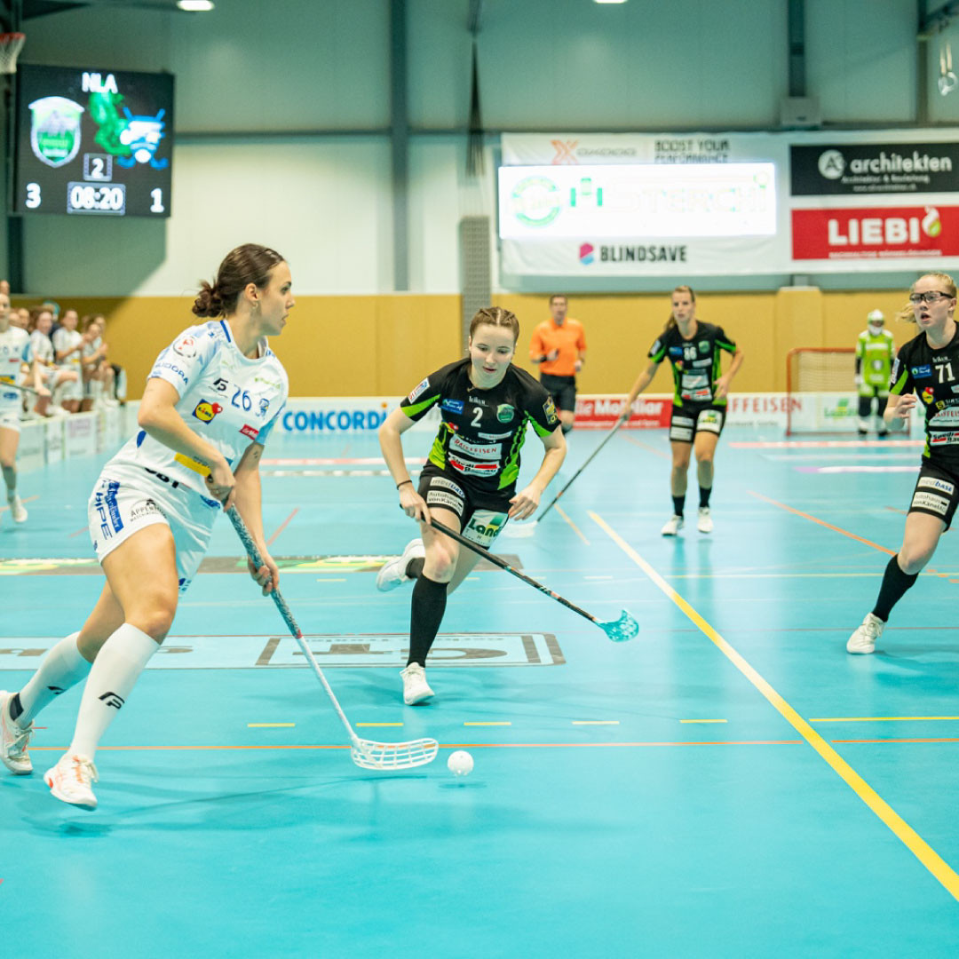 Céline Stettler im weissen Trikot am Ball mit drei Gegnerinnen