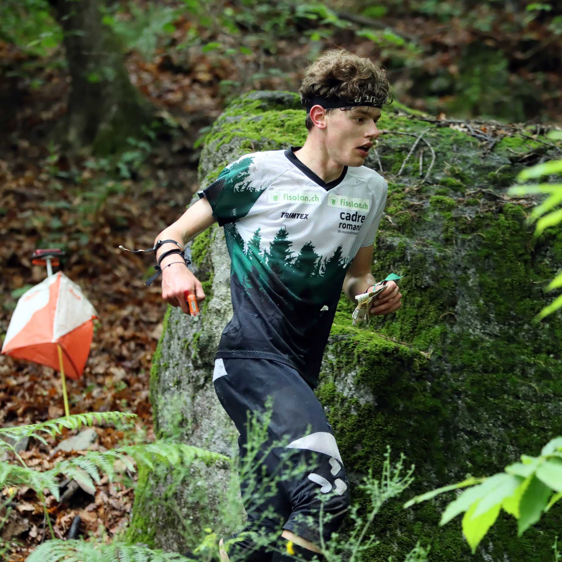 Matthieu Bührer in Sportkleidung im Wald am rennen neben einem OL-Posten
