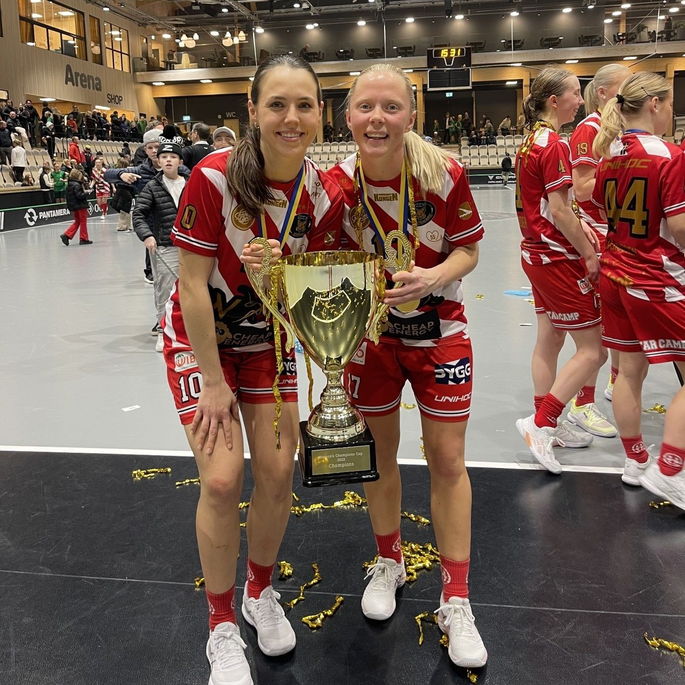 Céline Stettler en maillot rouge avec une coéquipière et une coupe à la main