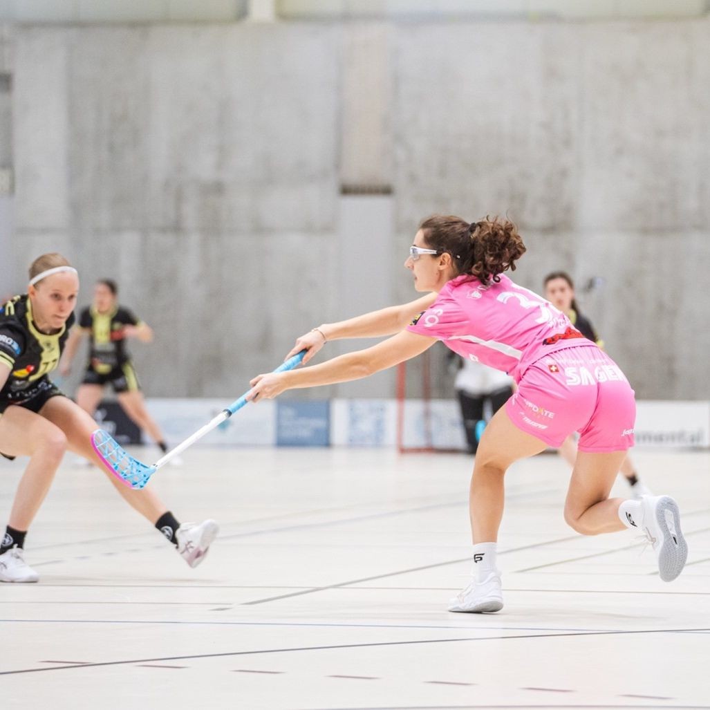 Marcia Wick en maillot rose sur le terrain en train de jouer à l'unihockey