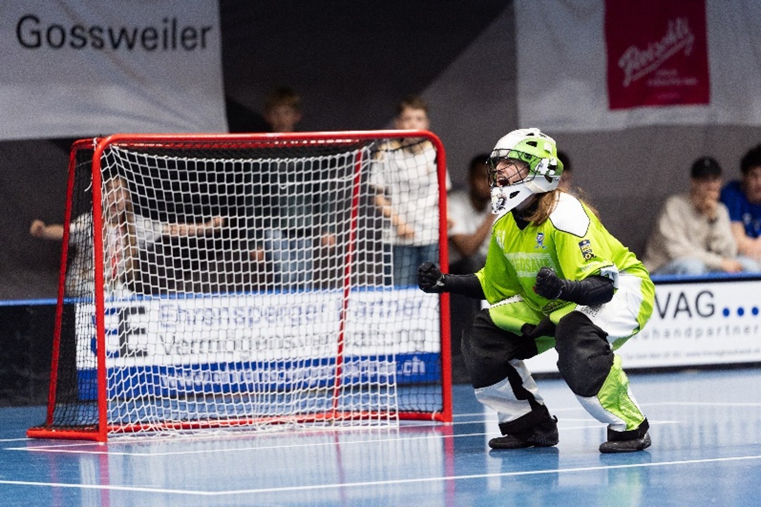 Livia Werz, en tenue de gardienne de but de unihockey, se réjouit en position accroupie face au public
